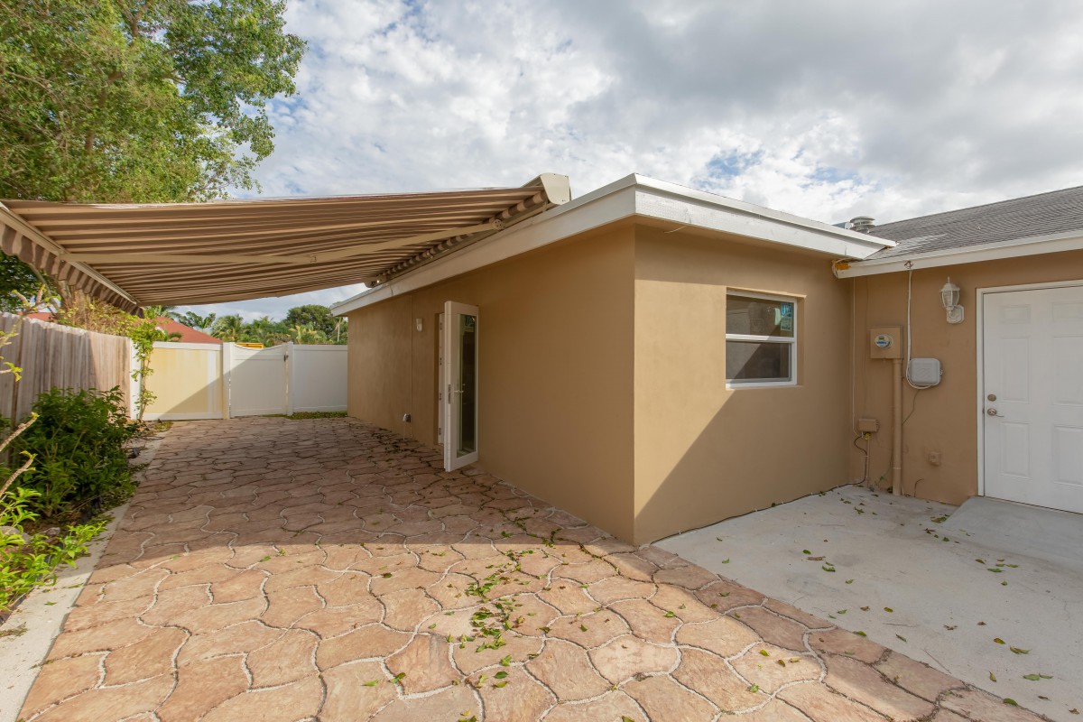 A small house with a patio area featuring an awning and stone path.