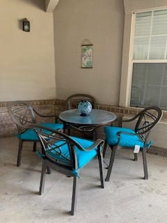 A cozy patio setup with a round table and four chairs featuring blue cushions.
