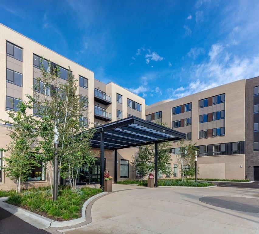 A modern residential building with a covered entrance and landscaped surroundings.