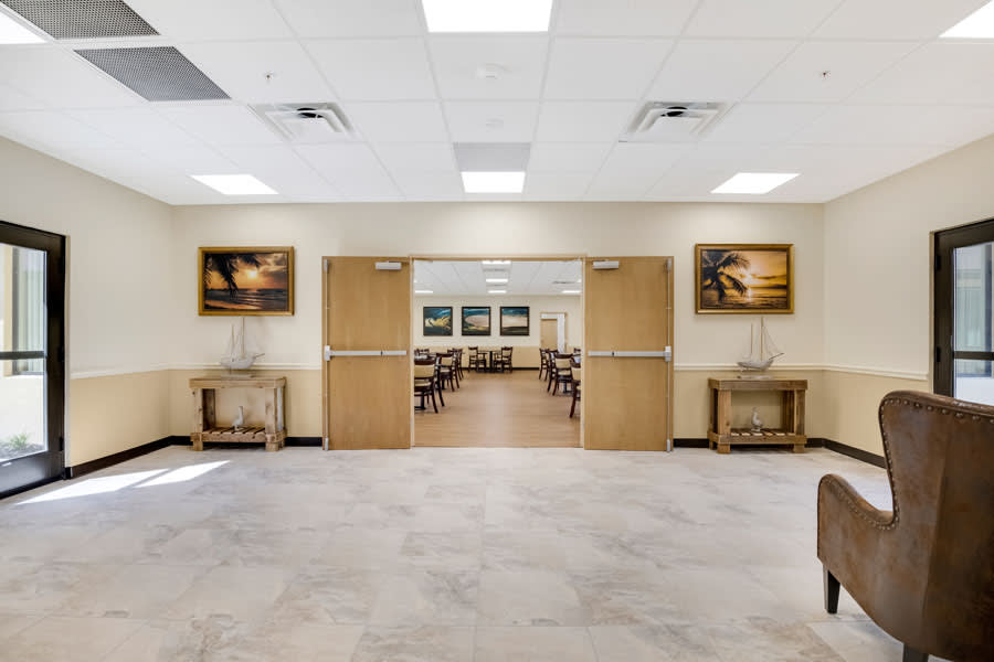 A spacious hallway featuring doors leading to a dining area, decorated with artwork on the walls.