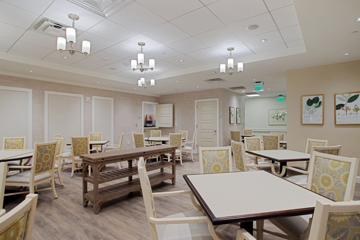 A modern dining area with neatly arranged tables and chairs, featuring elegant ceiling lights and wood flooring.