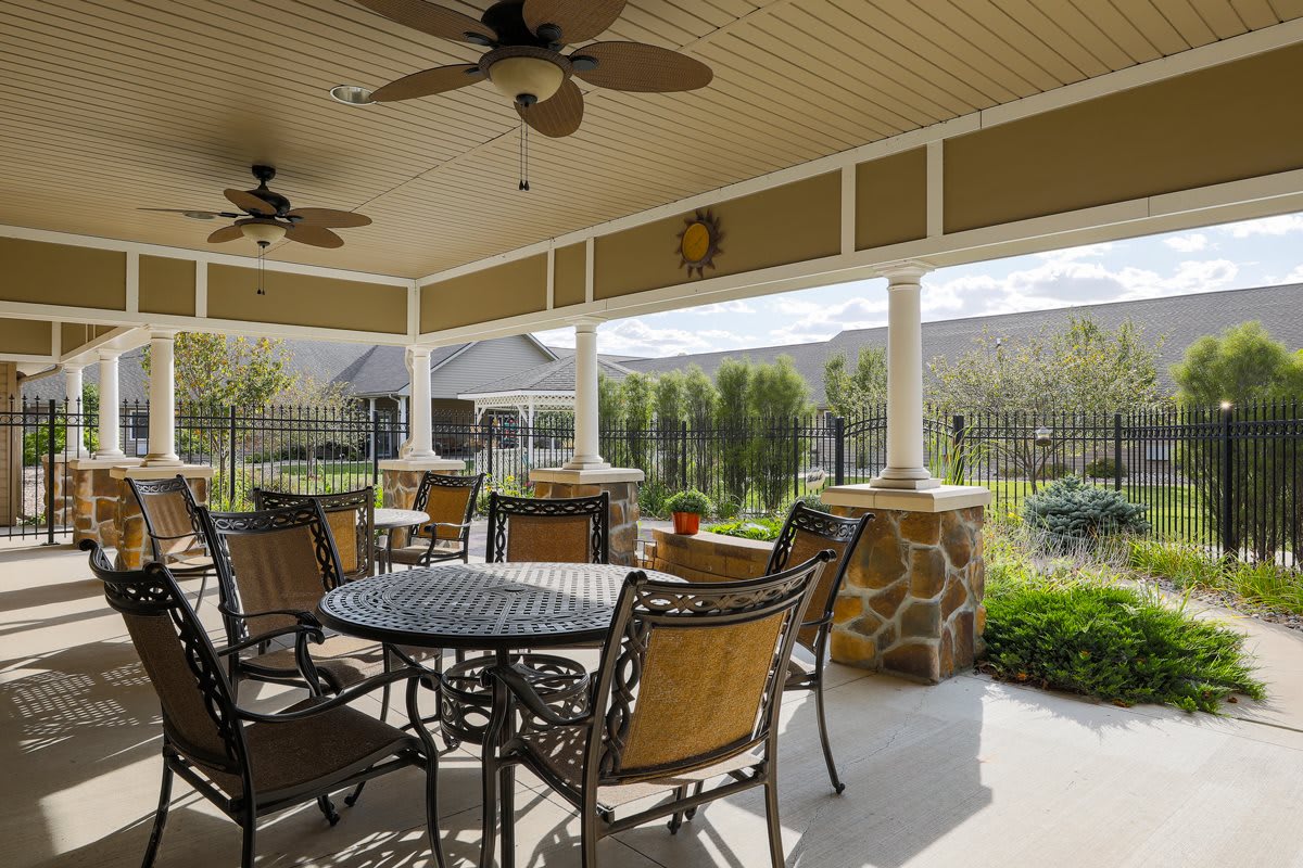 A cozy outdoor patio with ceiling fans, surrounded by lush greenery.