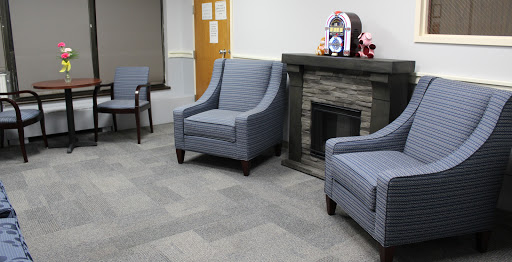 A cozy waiting area featuring two blue upholstered chairs and a decorative fireplace.