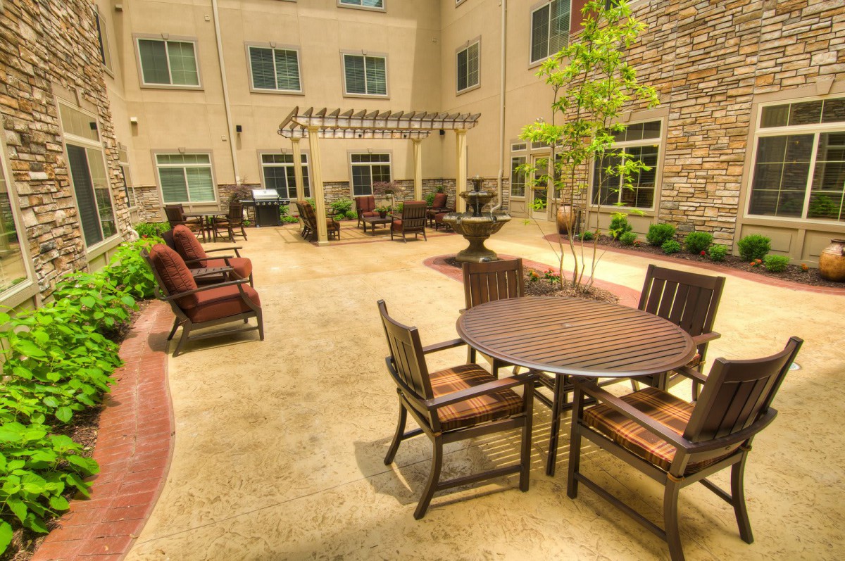 A sunny courtyard featuring outdoor seating with tables and chairs, ideal for relaxation.