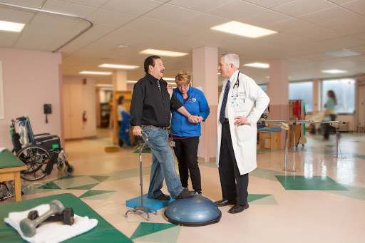 A doctor discusses therapy options with a patient and a healthcare professional in a hospital setting.