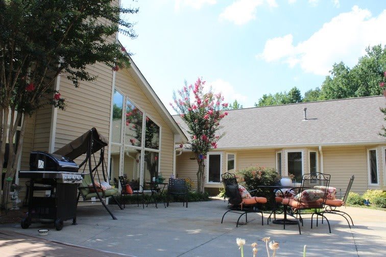 A cozy backyard with a patio, outdoor furniture, and swing beside a house.