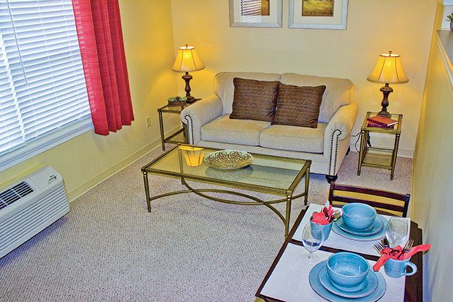 A cozy living room with a sofa, glass coffee table, and dining setup.