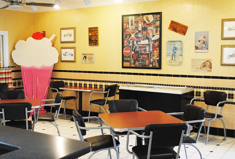 A retro-style diner interior featuring tables, chairs, and nostalgic decor.