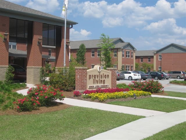 An apartment complex with neatly arranged landscaping and a central sign in a residential area.
