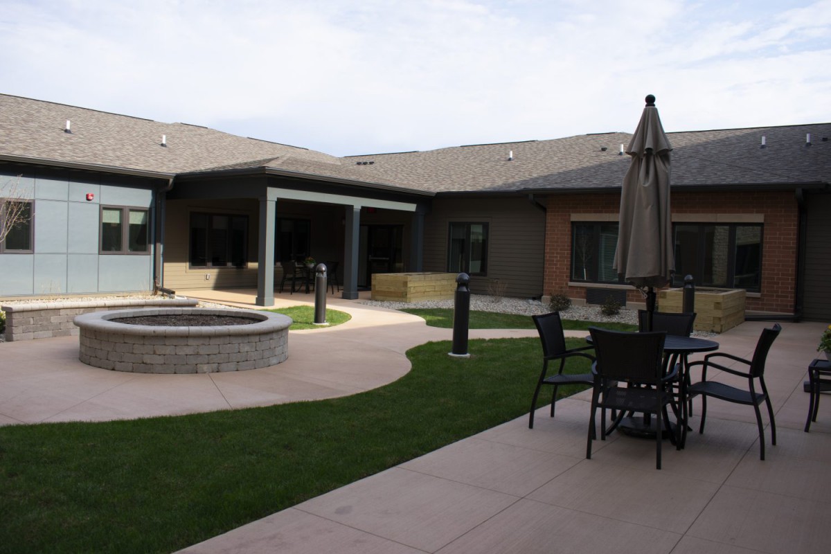 A modern courtyard featuring outdoor seating with a large umbrella and a well-maintained lawn.
