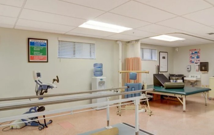 A well-equipped physical therapy room featuring parallel bars and an exercise bike.