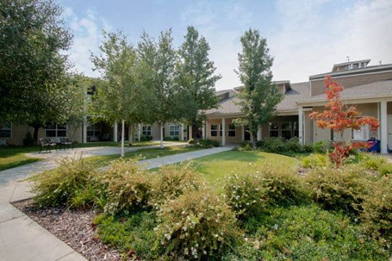 A scenic view of a building surrounded by a landscaped garden with trees and grass.