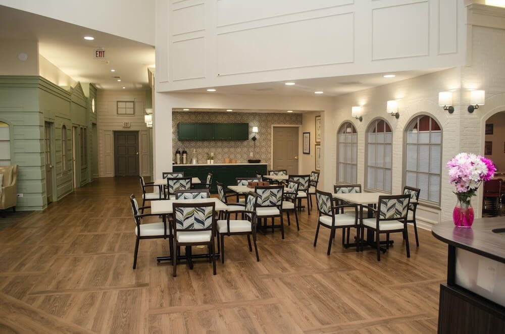 A modern cafe interior with neatly arranged tables and chairs, featuring a bar in the background.