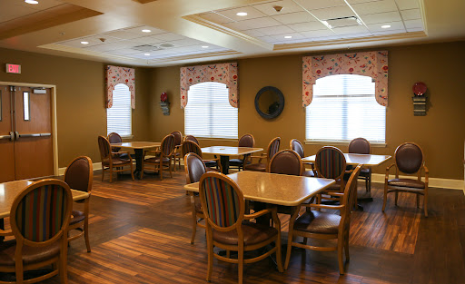 A spacious dining room featuring wooden tables and chairs, with large windows allowing natural light to fill the space.