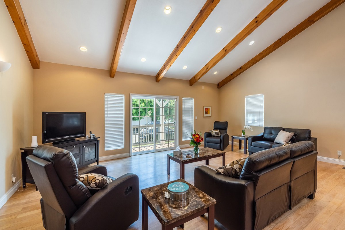 A modern living room with wood beams, sofas, and a television.