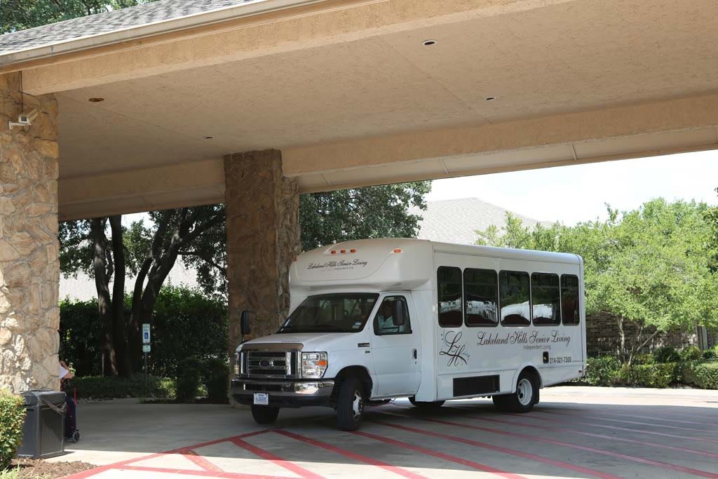 A shuttle bus parked under a covered entrance.