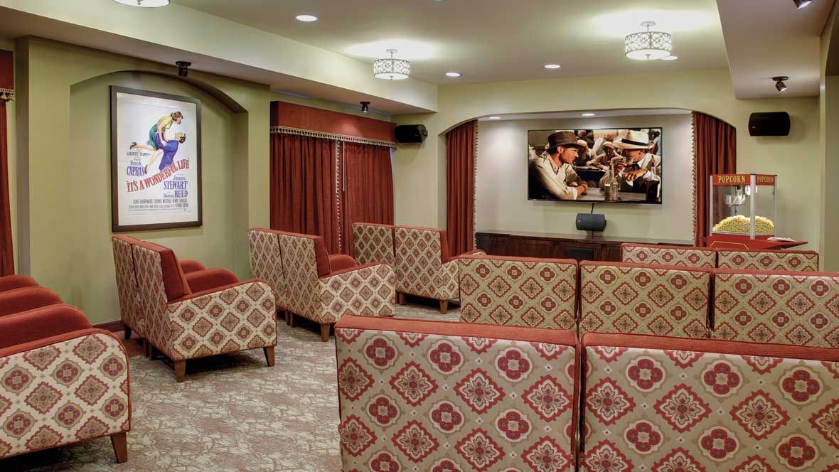 A comfortable lounge area with patterned chairs and a large television on the wall.