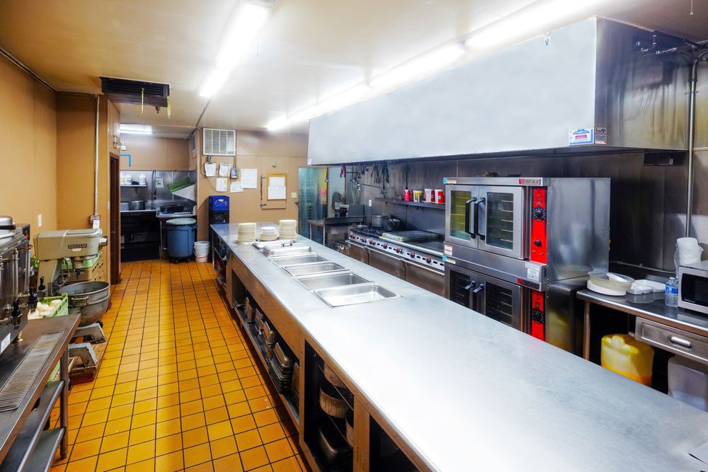 A clean and organized commercial kitchen with stainless steel countertops and modern appliances.