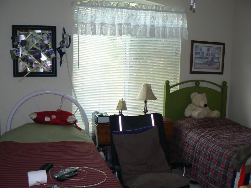 A bedroom with two beds, a stuffed animal, and a window with curtains.