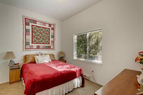 Cozy bedroom with a quilt hanging on the wall and a large window providing natural light.