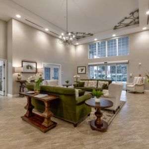 A spacious and elegantly designed living room featuring a chandelier, large windows, and luxurious furniture.
