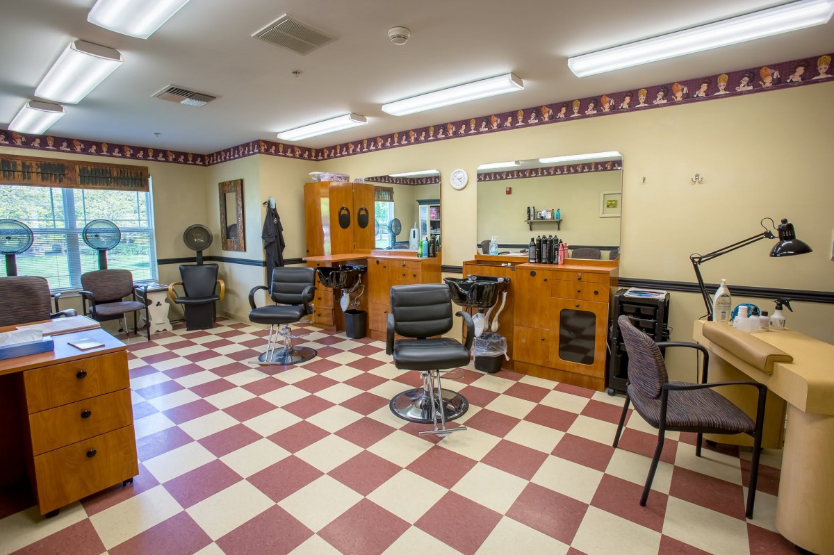 An empty barbershop with checkered flooring and several styling chairs.