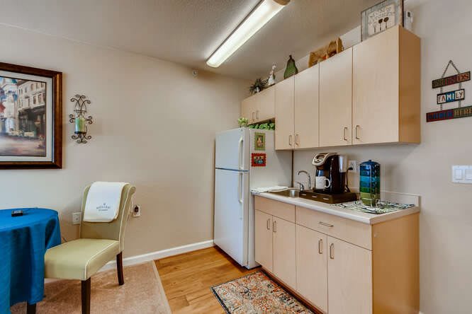 A compact kitchen setup with a refrigerator, cabinets, and coffee maker.