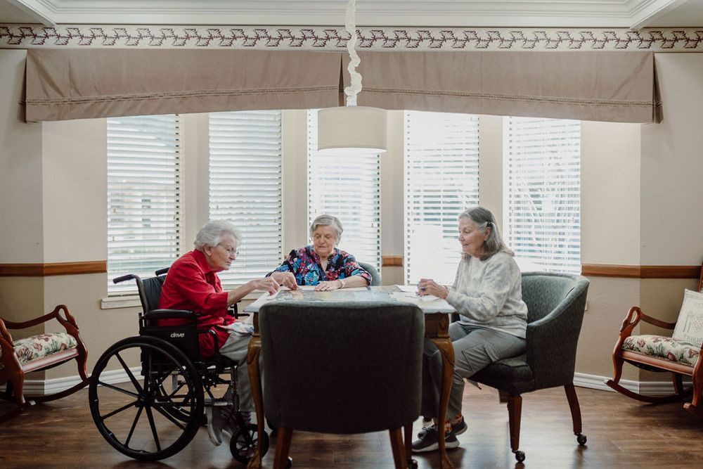 A group of elderly individuals engaging in a social activity around a table in a well-lit room.