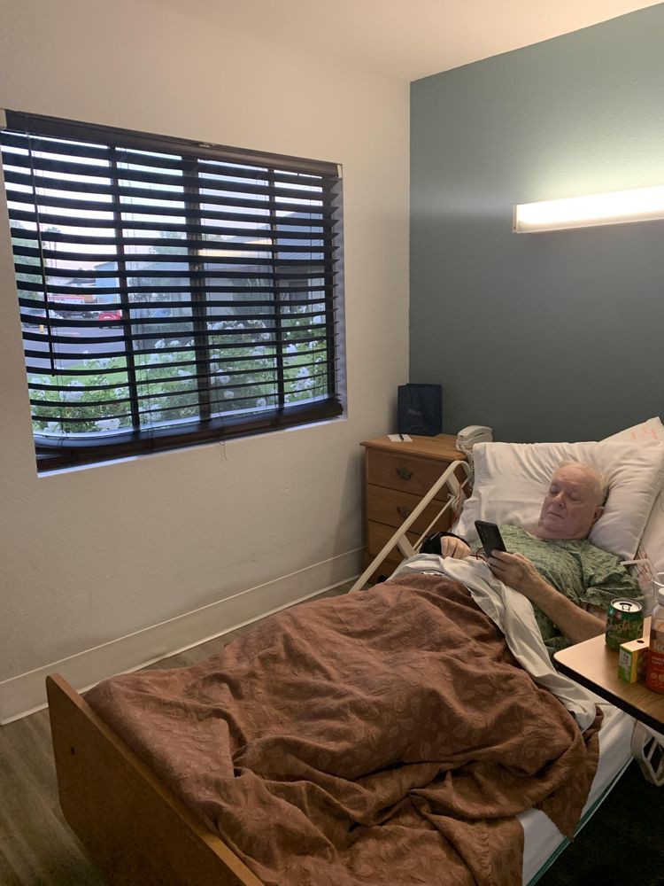 A cozy room with a hospital bed beside a window with blinds.