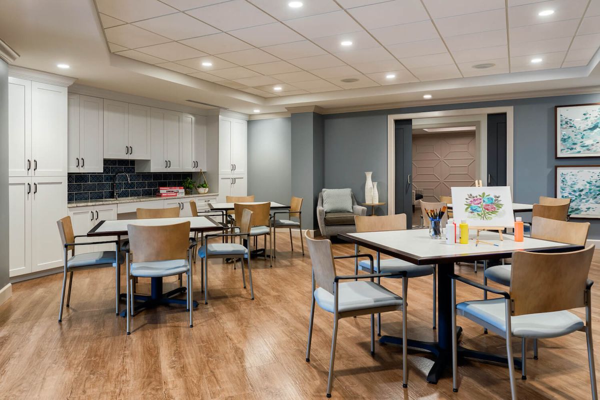 A modern indoor dining area with chairs and tables on a wooden floor.