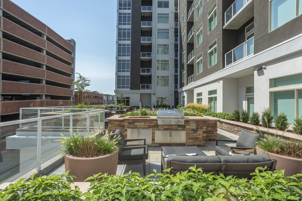 Modern apartment complex with spacious outdoor seating area and greenery.