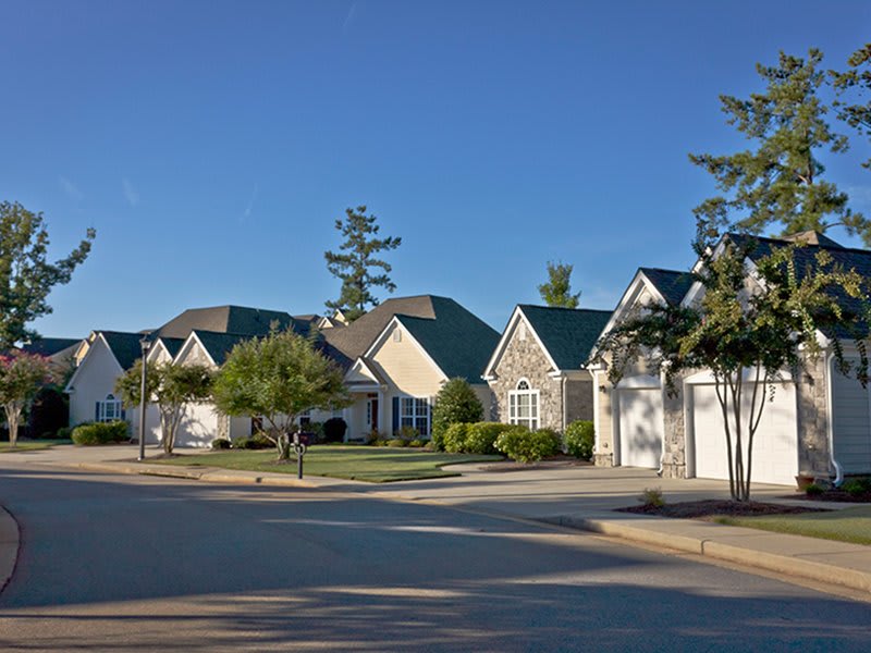 A quiet suburban neighborhood with neatly arranged houses under a clear blue sky.