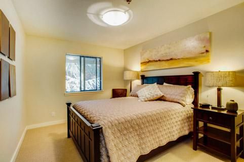 A cozy bedroom with a large bed, bedside lamp, and window.