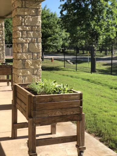 A beautifully crafted wooden planter filled with herbs, situated on a sunny patio.