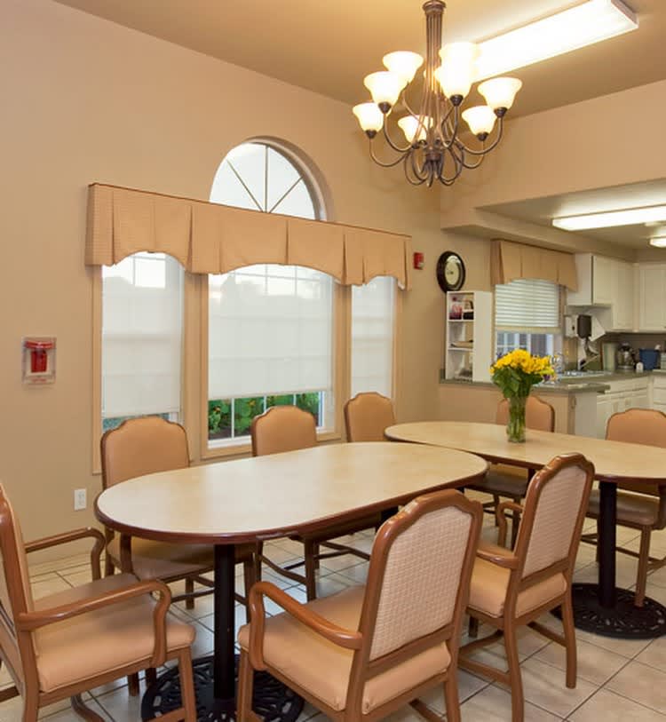 A cozy dining room setup with a table and chairs, adorned with a chandelier and adjacent to a kitchen area.
