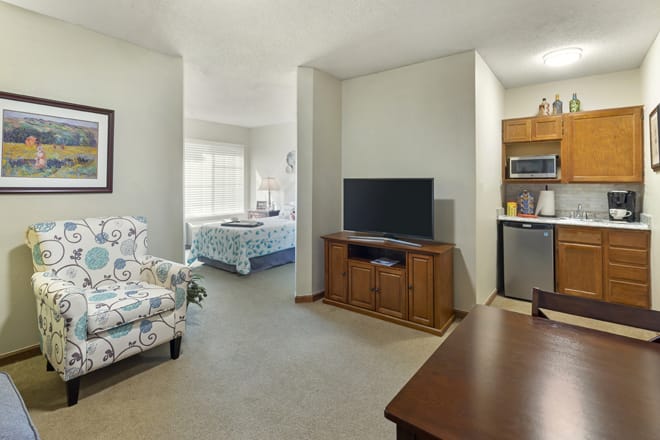 An open-plan apartment with a living room, adjacent bedroom, and a small kitchen area.