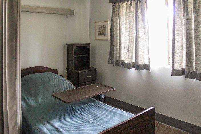 An empty hospital room with a bed and side furniture.