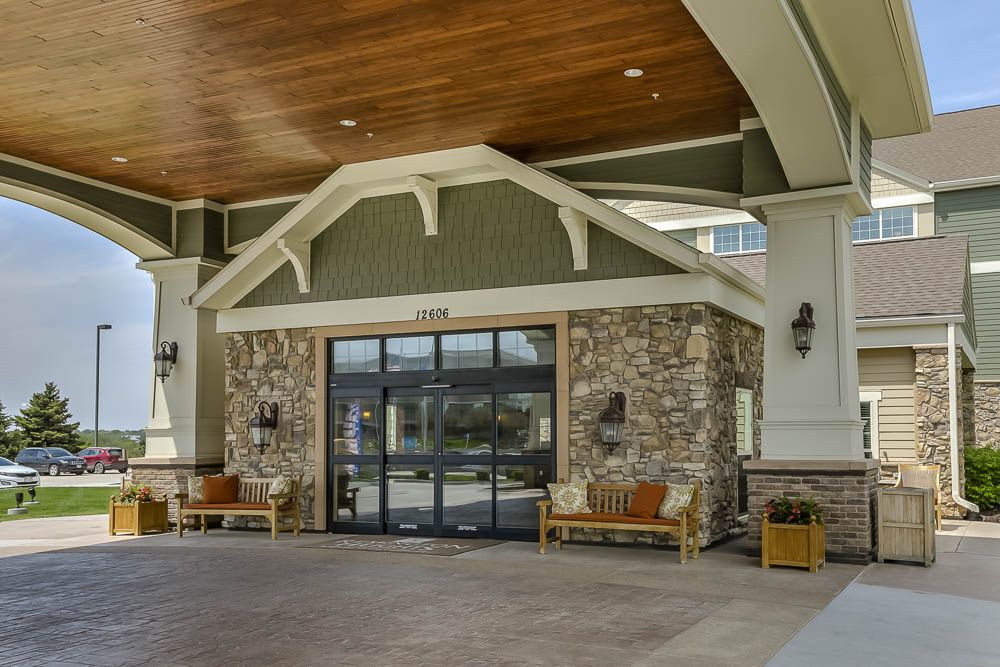 Entrance of a modern building with a stone facade and wooden benches.