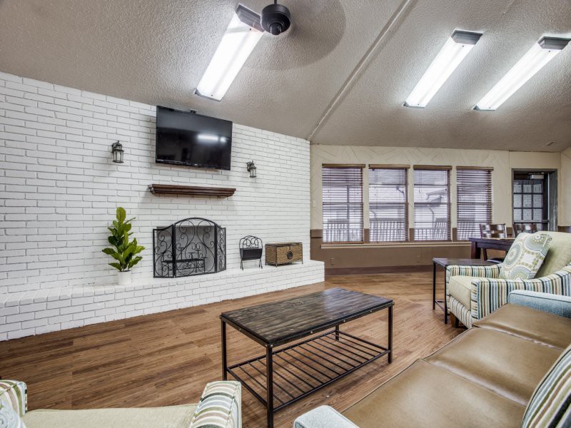 A modern living room featuring a brick fireplace, mounted television, and wooden flooring.