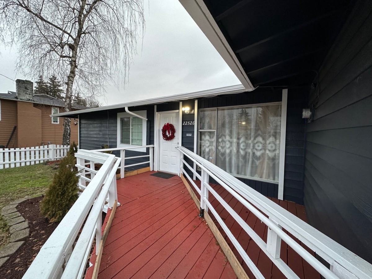 A welcoming house with a red ramp leading to the front door adorned with a wreath.
