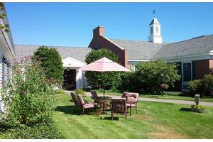 A sunny garden with outdoor seating and an umbrella near a building.