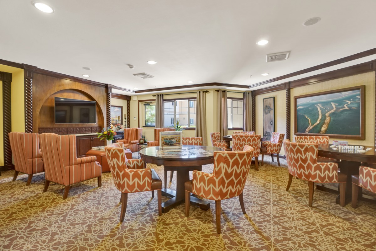 A warmly decorated living room with patterned chairs and a central round table.