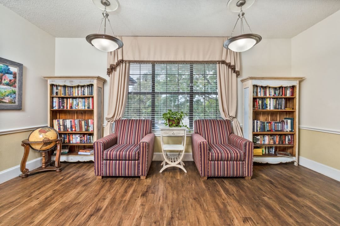 A cozy reading nook with armchairs and bookshelves by a large window.