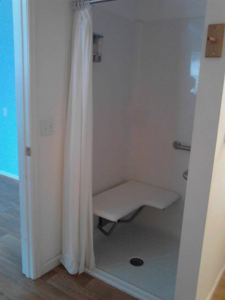 Accessible shower with a seat and curtain.