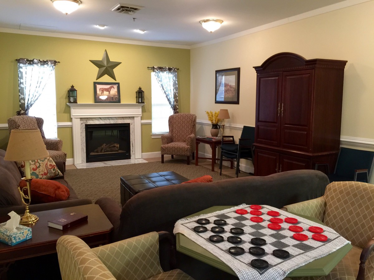 A cozy living room featuring a fireplace, comfortable seating, and a checkerboard game setup.