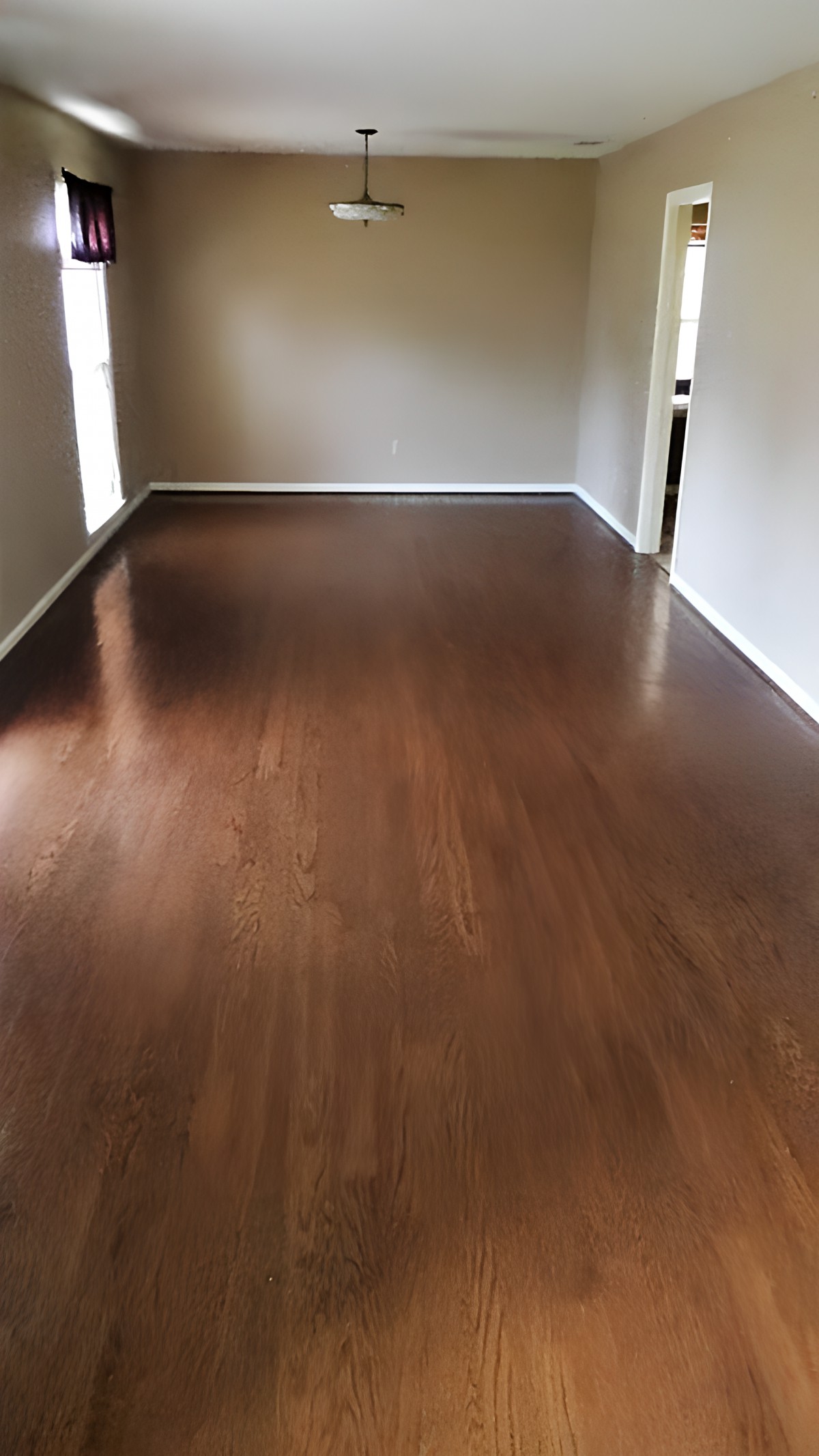 An empty room with sleek hardwood flooring and natural light streaming in.