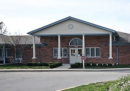 A brick building with columns at the entrance and a driveway in front.