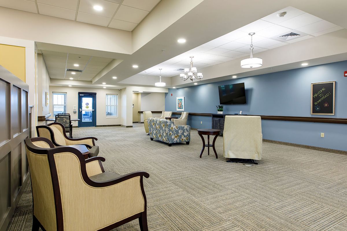 A spacious and well-lit waiting room with comfortable seating and a television.