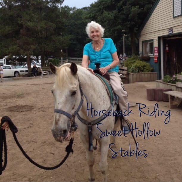 Elderly woman enjoying horseback riding outdoors at Sweet Hollow Stables.