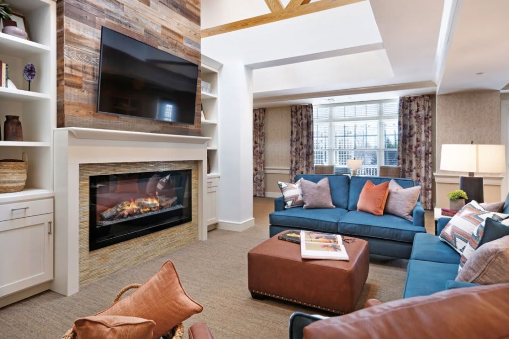 A cozy and modern living room featuring a fireplace, comfortable seating, and a large window providing ample natural light.